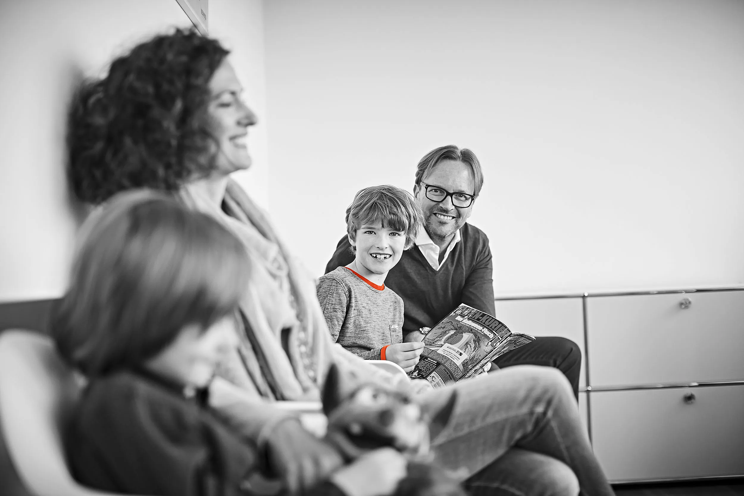 Eine Frau mit Kindern sitzt im Wartebereich mit Dr. Ritter